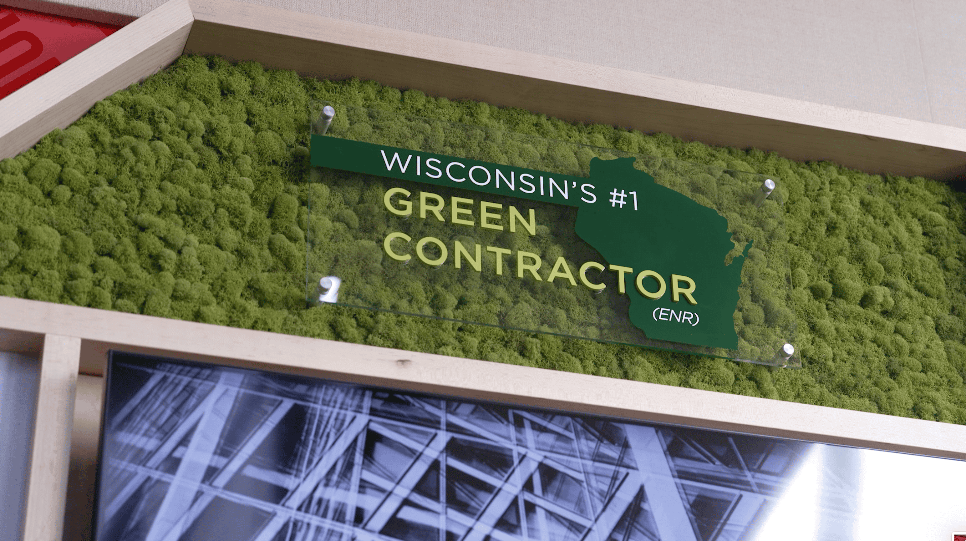 Wall display at Findorff headquarters showcasing Thysse’s facility branding work. Features green moss backdrop with a transparent sign reading 'Wisconsin’s #1 Green Contractor (ENR)' overlaid on a silhouette of Wisconsin.